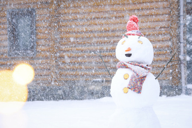 Funny snowman with hat and scarf outdoors on snowy day. Winter vacation