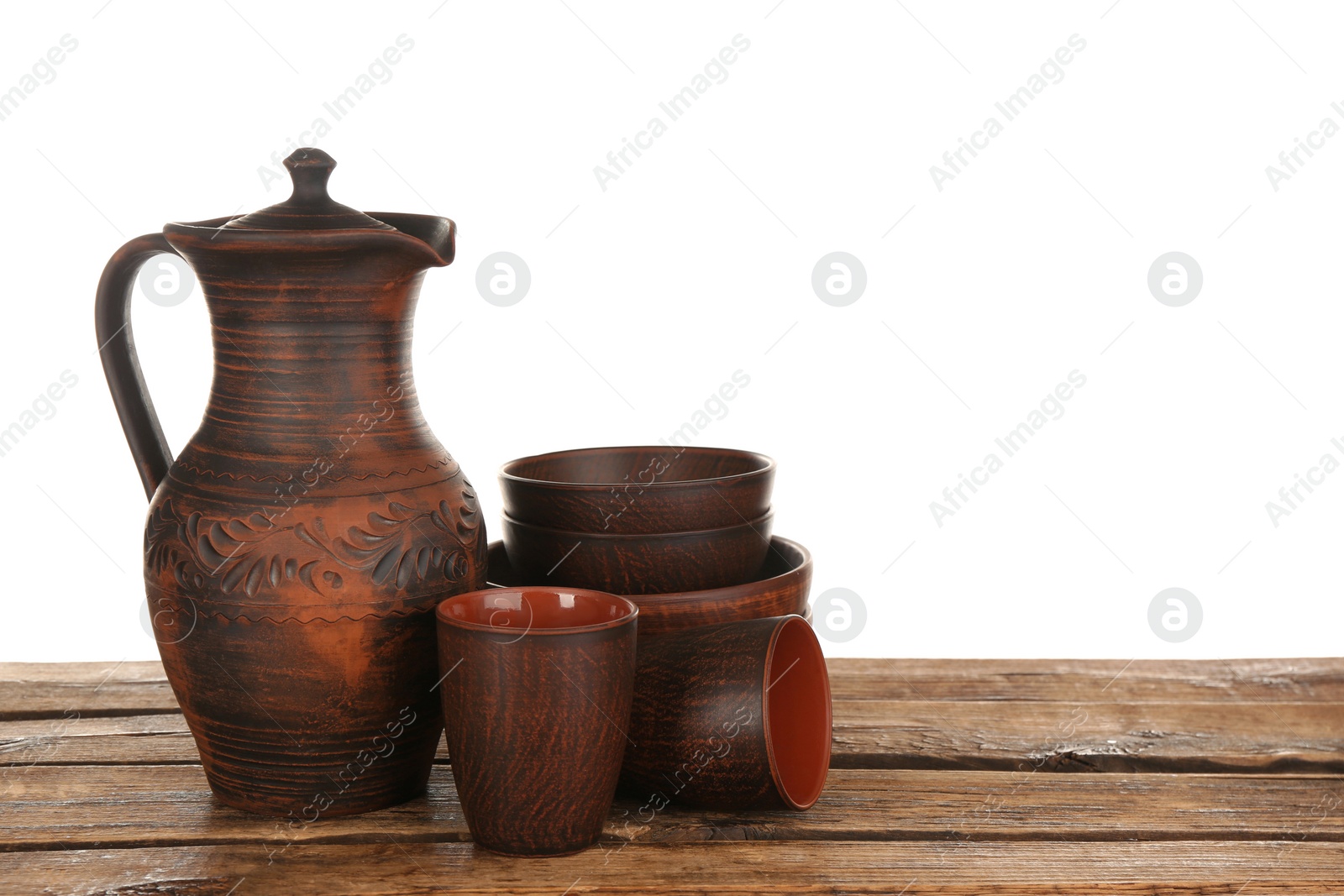 Photo of Different clay dishware on wooden table against white background