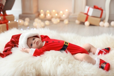Photo of Cute baby in Christmas costume on fur rug at home