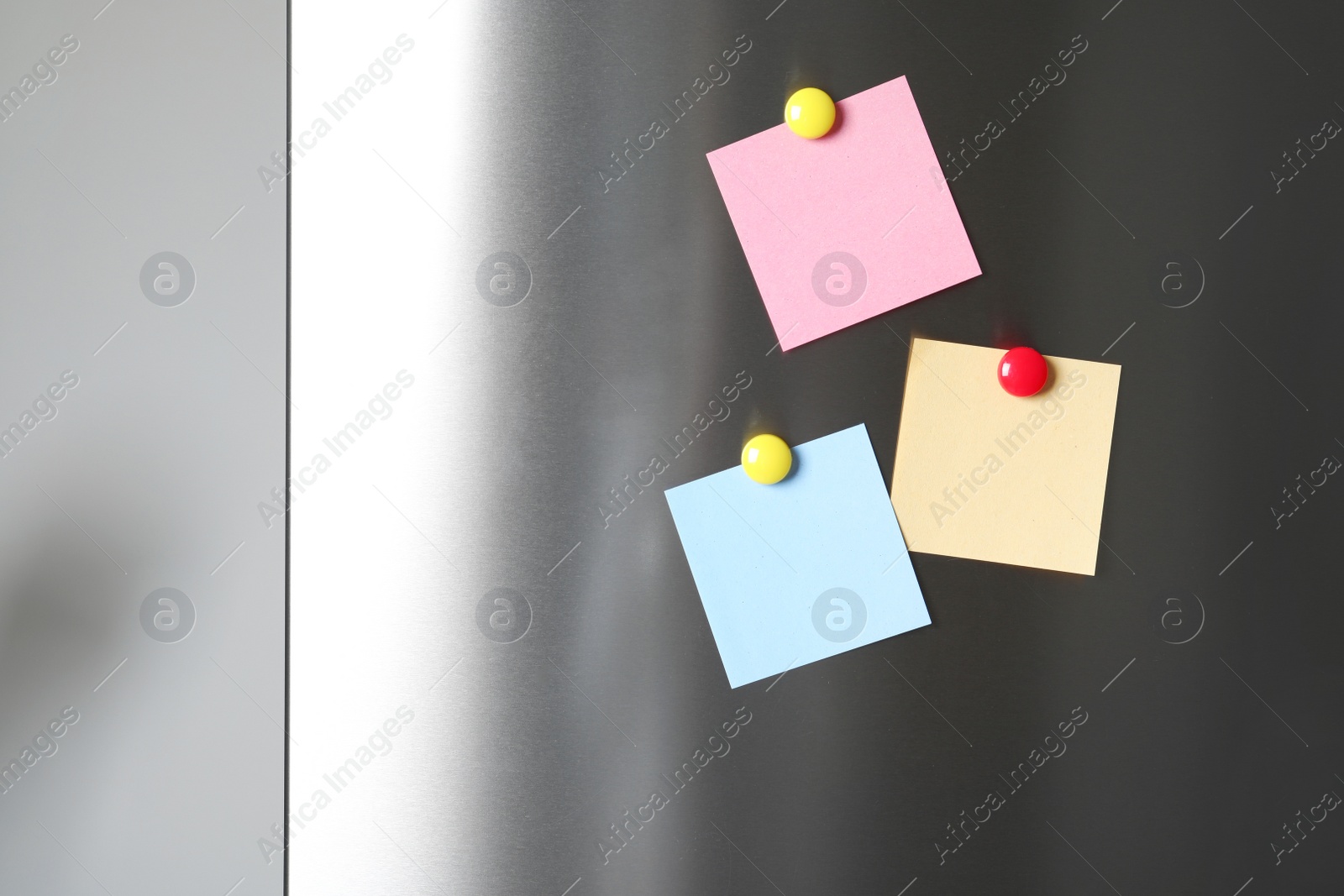 Photo of Blank notes with colorful magnets on refrigerator door. Space for text