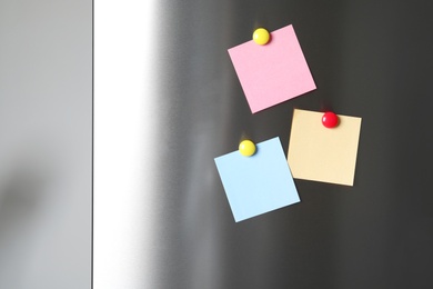 Blank notes with colorful magnets on refrigerator door. Space for text