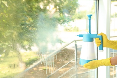 Janitor cleaning window with detergent indoors, closeup