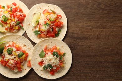 Photo of Delicious tacos with vegetables and lime on wooden table, top view. Space for text