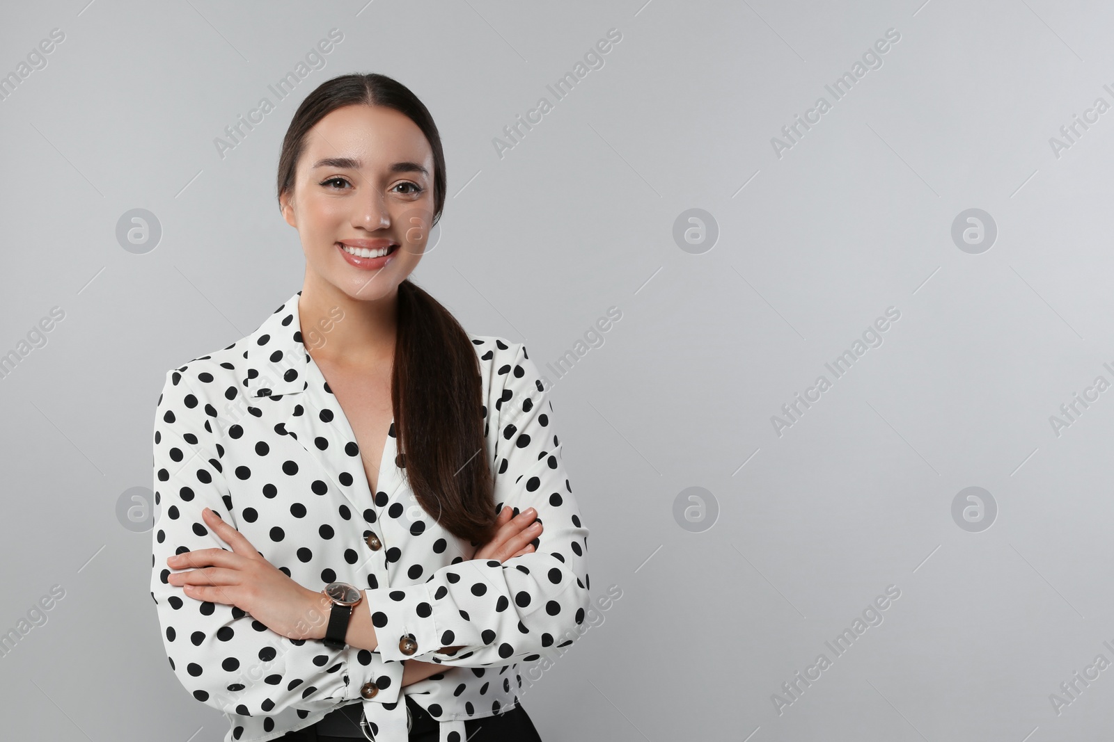 Photo of Portrait of beautiful young woman in polka dot blouse on light grey background. Space for text