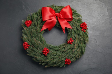 Photo of Beautiful Christmas wreath with red berries and bow on black background