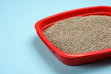 Cat litter tray with filler on light blue background, closeup