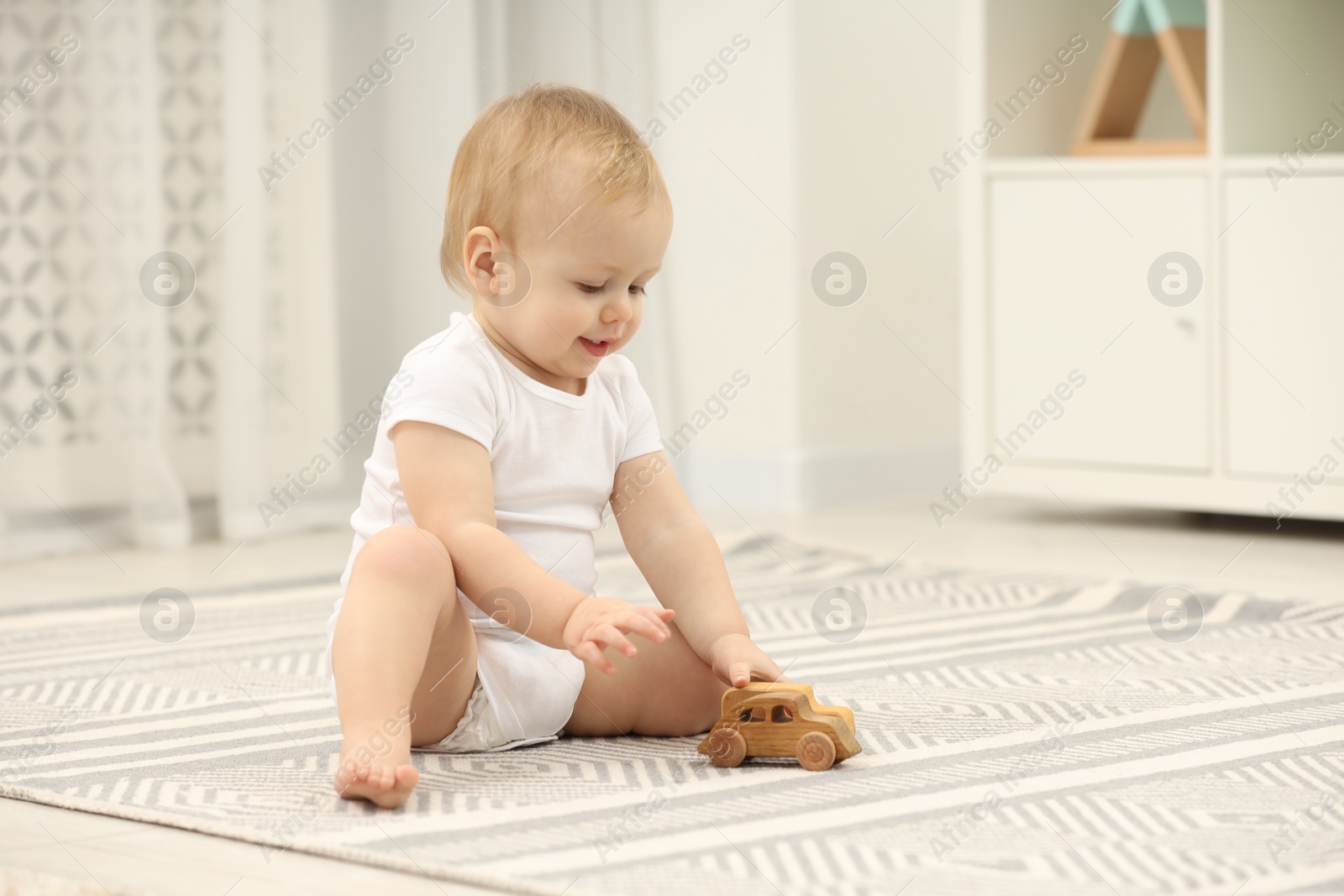 Photo of Children toys. Cute little boy playing with wooden car on rug at home