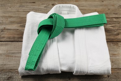Photo of Green karate belt and white kimono on wooden background