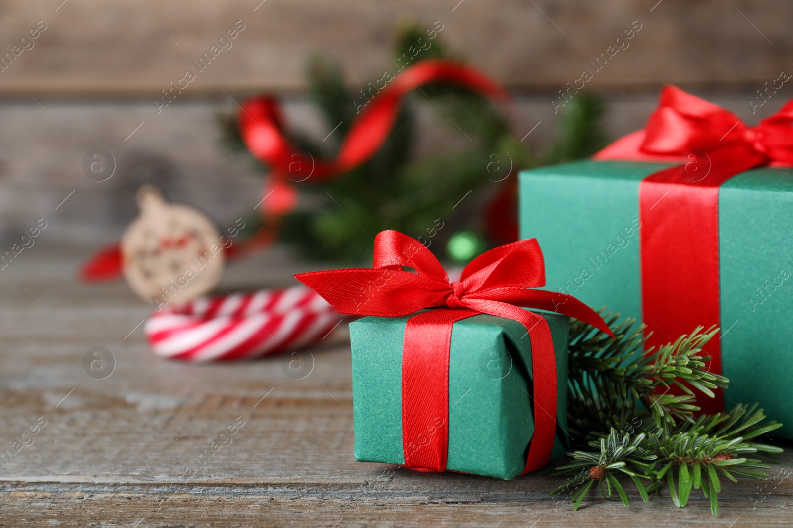 Photo of Christmas gift boxes and fir branches on wooden table, closeup. Space for text