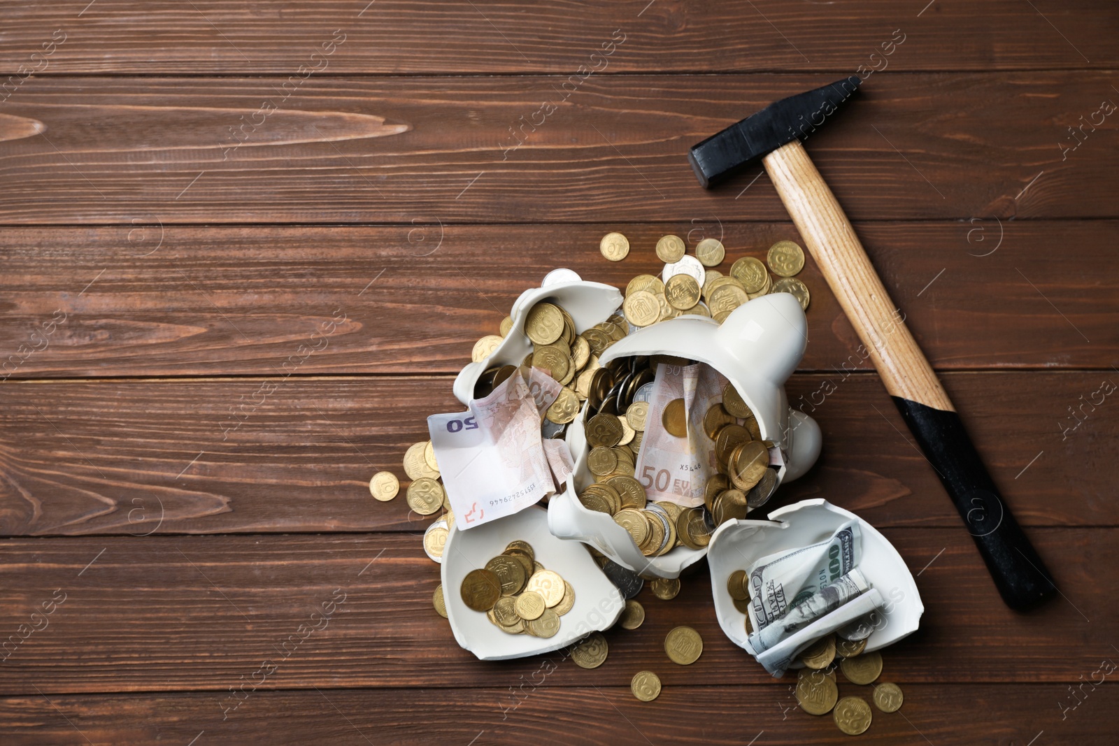 Photo of Broken piggy bank with money and hammer on wooden background, top view. Space for text