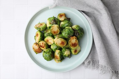 Photo of Delicious roasted Brussels sprouts on white tiled table, top view