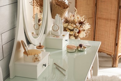 Wooden dressing table with decorative elements and makeup products in room