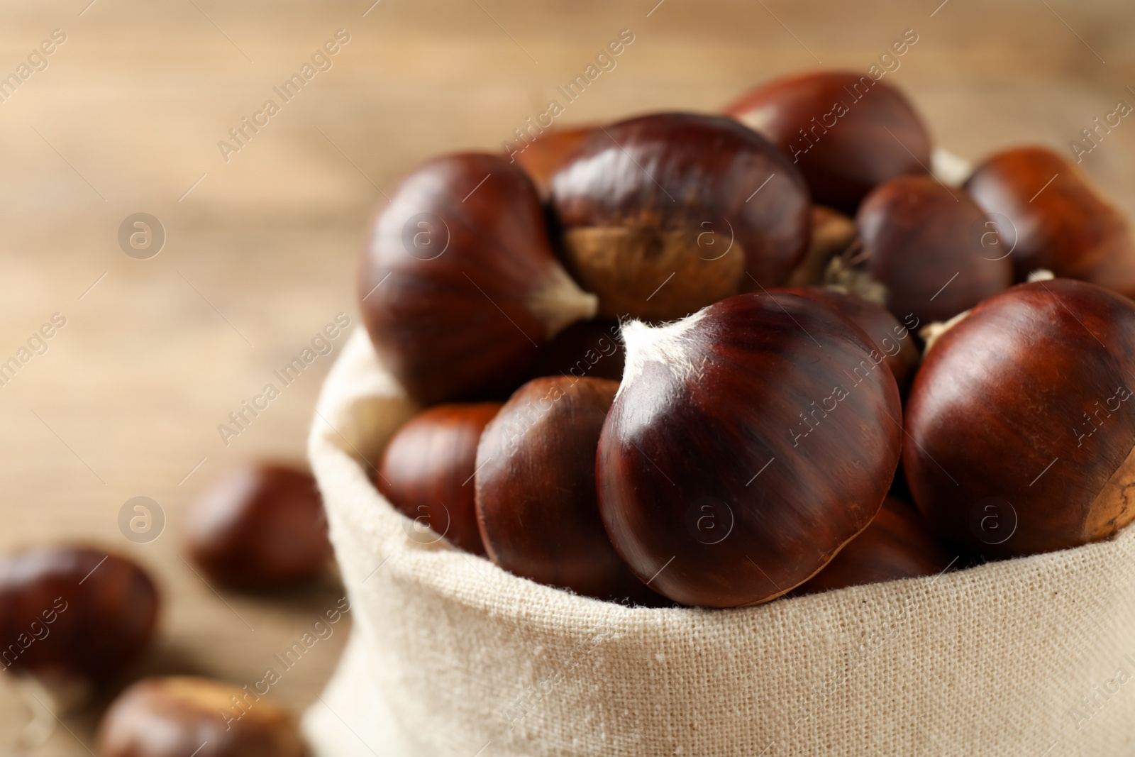 Photo of Fresh sweet edible chestnuts in sack, closeup