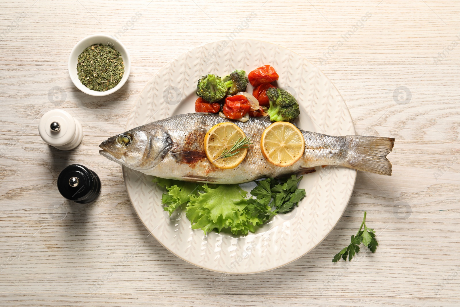 Photo of Delicious baked fish and vegetables served on wooden table, flat lay