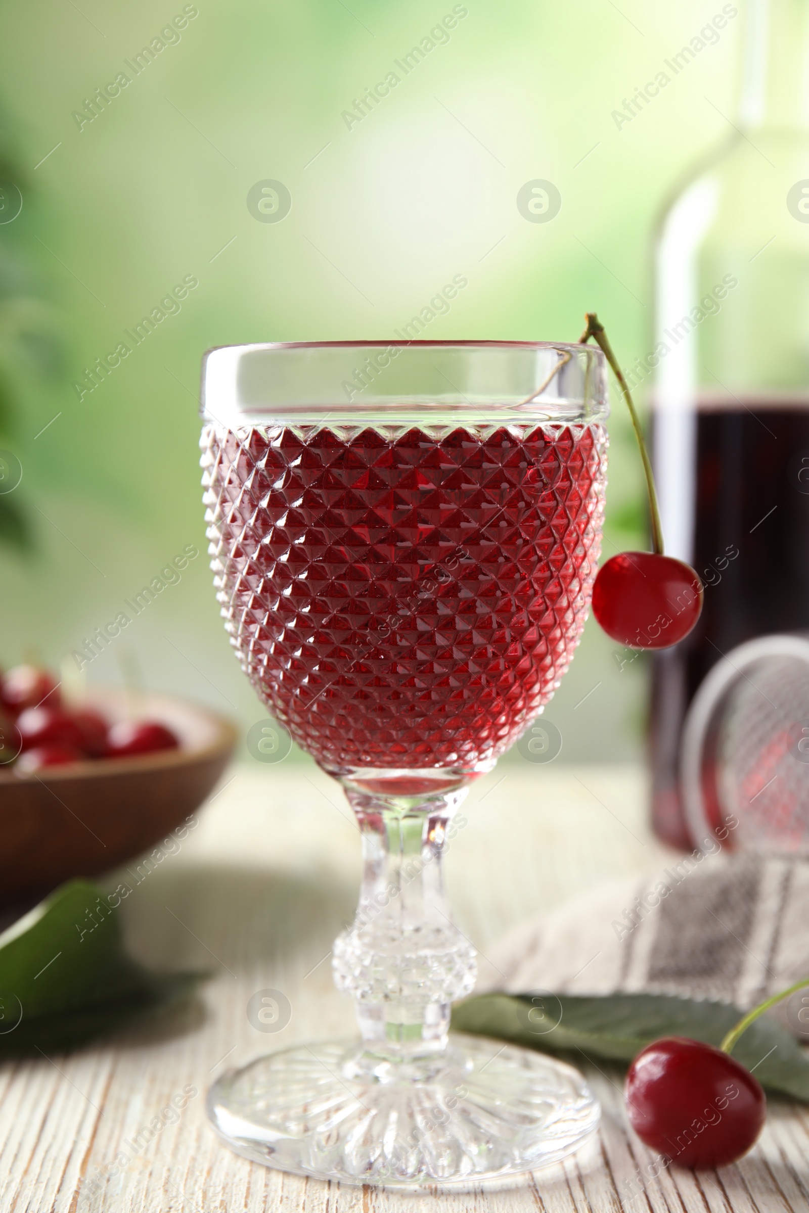 Photo of Delicious cherry wine with ripe juicy berries on white wooden table