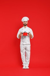Professional chef with cooking pot on red background
