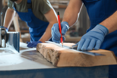 Photo of Professional carpenters working with wood in shop, closeup
