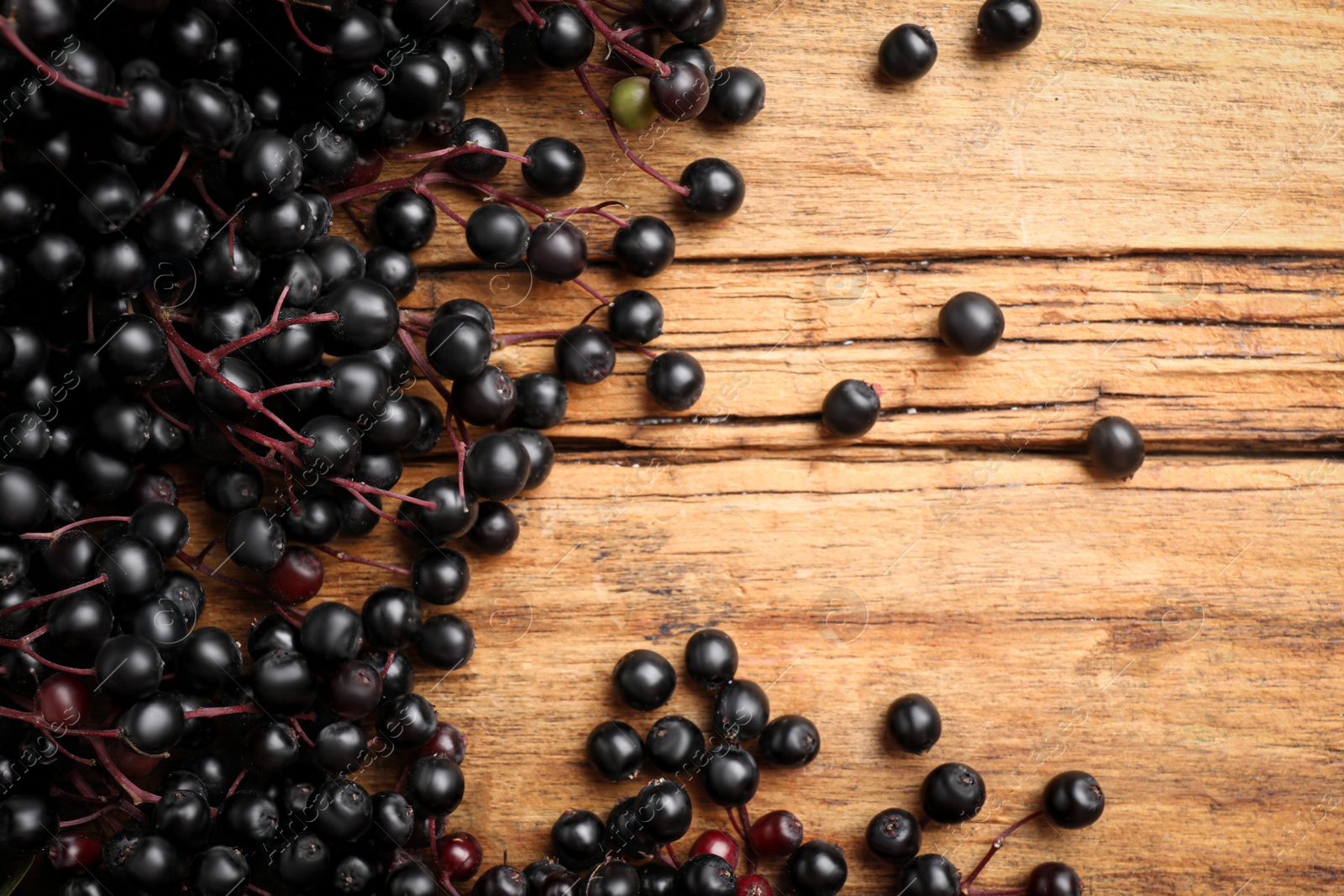 Photo of Elderberries (Sambucus) on wooden table, flat lay