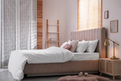 Cozy bed with soft linens in light room