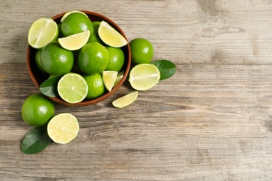 Photo of Tasty ripe limes in bowl on wooden table, top view