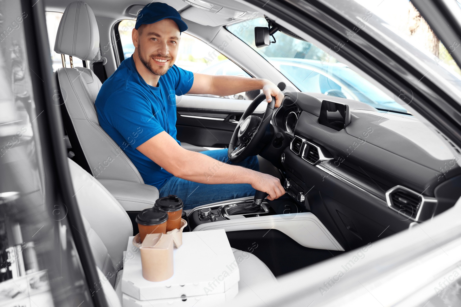 Photo of Male courier with orders in car. Food delivery service