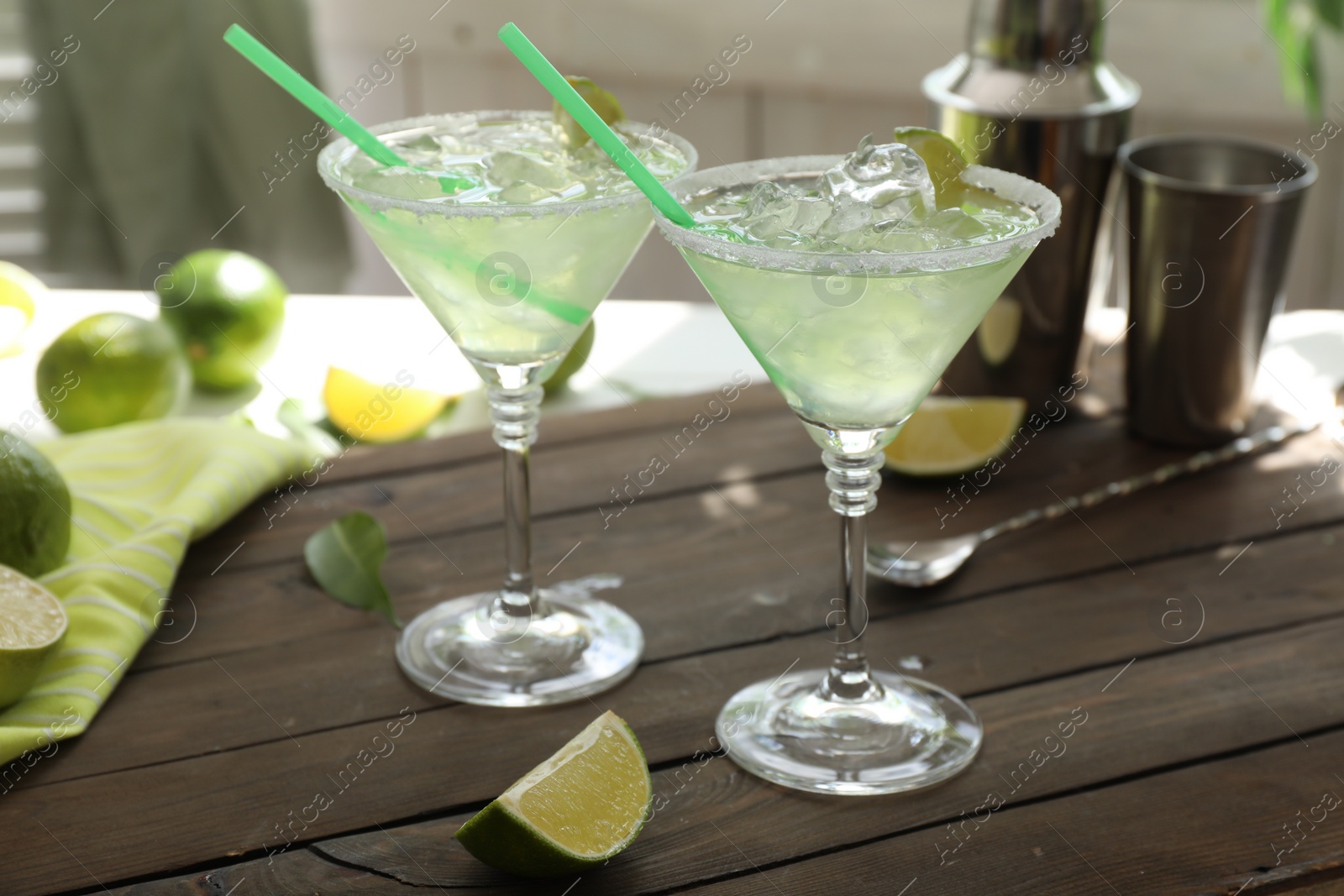 Photo of Delicious Margarita cocktail in glasses and lime on wooden table, closeup