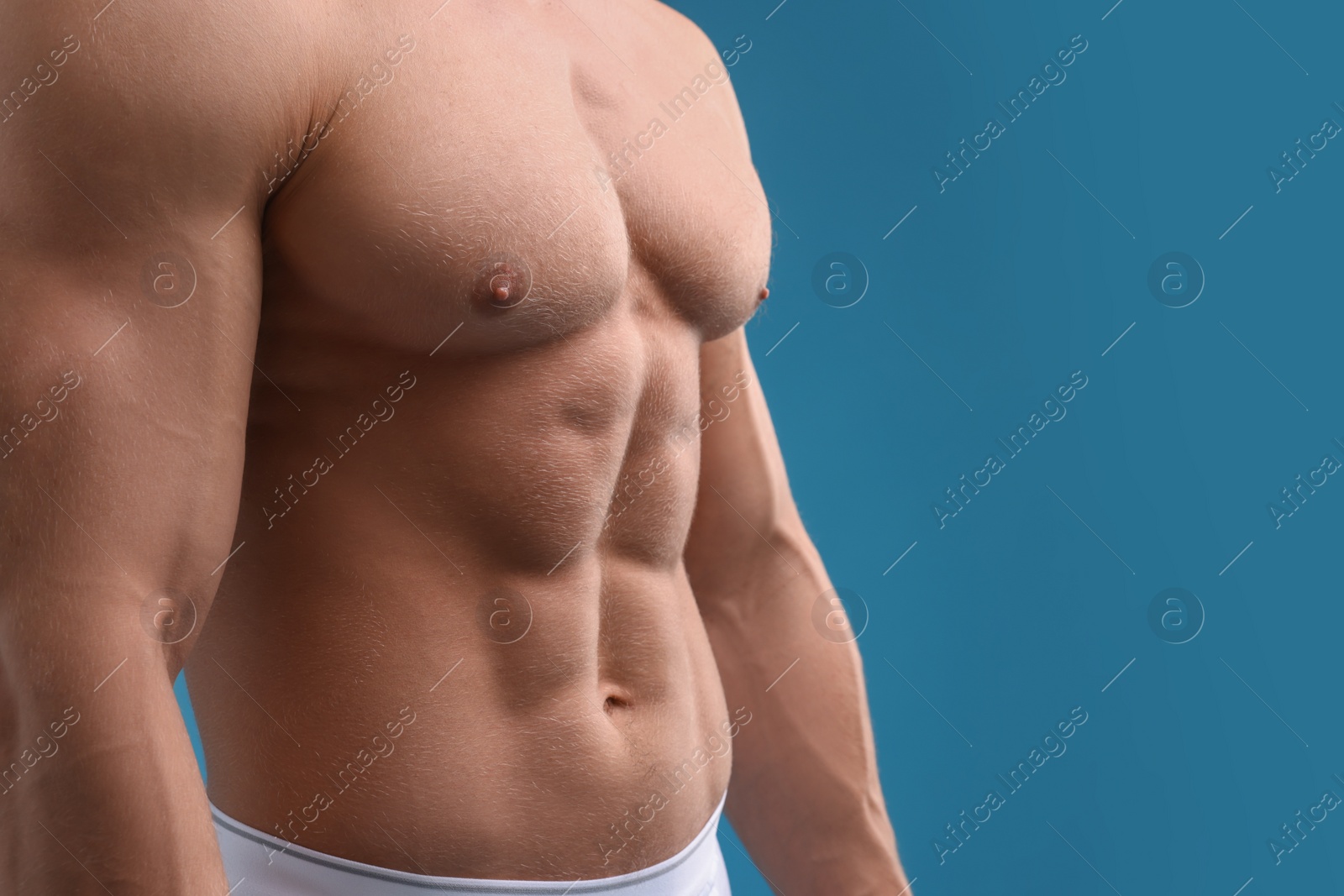 Photo of Muscular man showing abs on light blue background, closeup and space for text. Sexy body