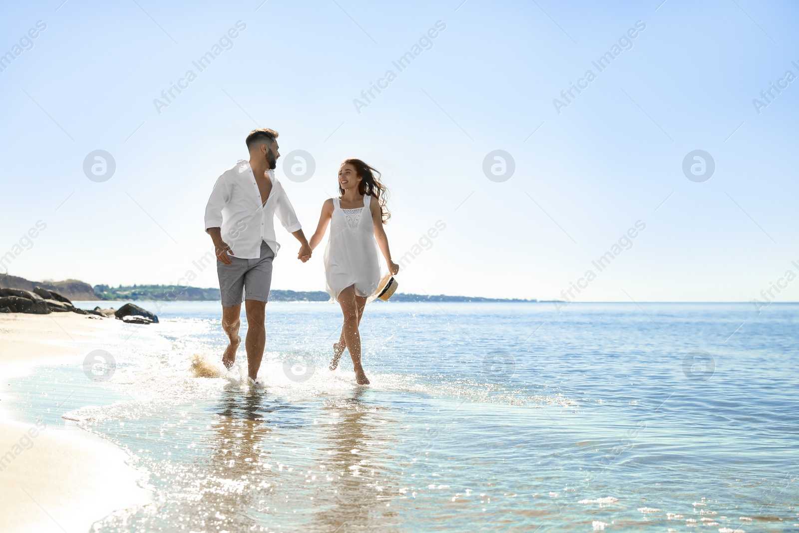 Photo of Happy young couple running on beach near sea. Honeymoon trip