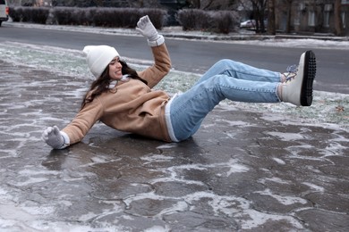 Photo of Young woman fallen on slippery icy pavement outdoors
