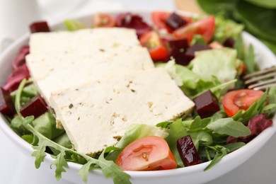 Photo of Bowl of tasty salad with tofu and vegetables on table, closeup