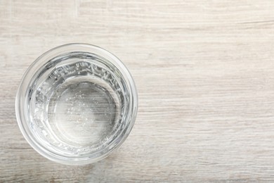 Photo of Glass of soda water on white wooden table, top view. Space for text