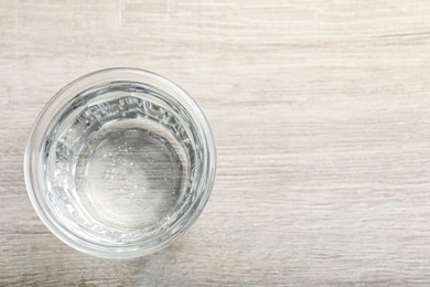 Glass of soda water on white wooden table, top view. Space for text