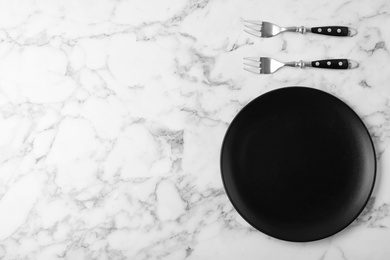 Photo of Forks and empty plate on marble table, flat lay with space for text