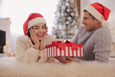 Photo of Boyfriend giving Christmas gift box to his girlfriend at home