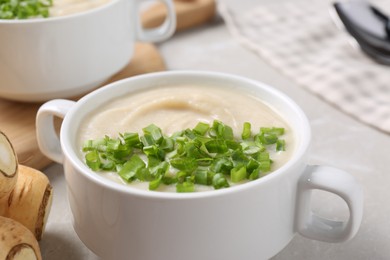 Photo of Bowl with tasty creamy soup of parsnip on light grey table, closeup