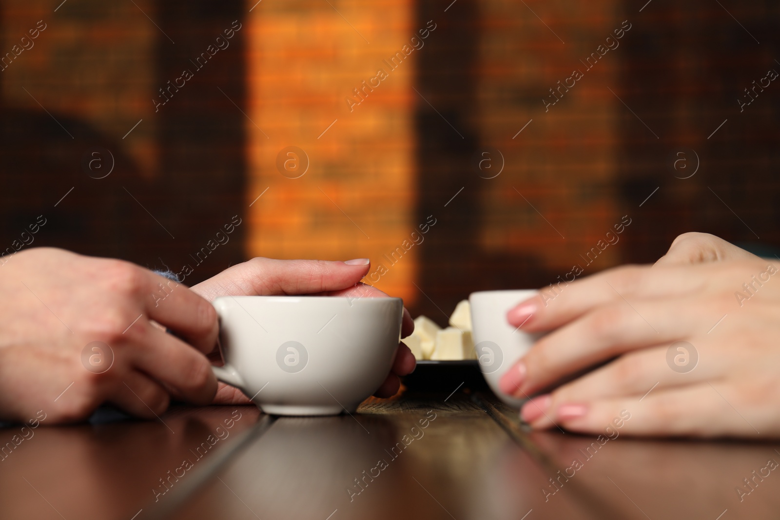 Photo of Women having coffee break at wooden table in cafe, closeup