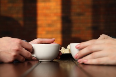 Photo of Women having coffee break at wooden table in cafe, closeup