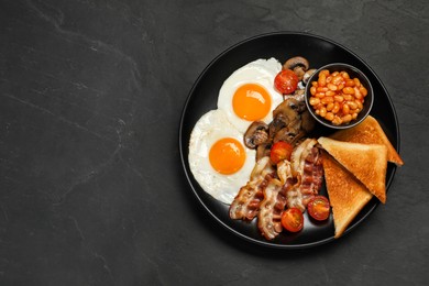 Photo of Plate of fried eggs, mushrooms, beans, bacon, tomatoes and toasted bread on black table, top view with space for text. Traditional English breakfast