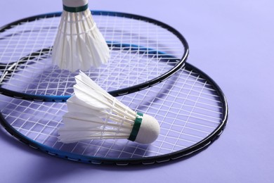 Photo of Feather badminton shuttlecocks and rackets on violet background, closeup