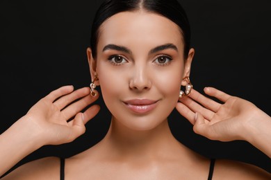 Photo of Young woman with elegant pearl earrings on black background