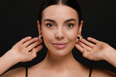 Young woman with elegant pearl earrings on black background