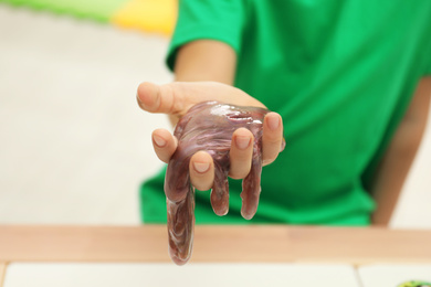 Photo of Little boy holding slime in room, closeup