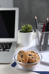 Photo of Bowl with chocolate chip cookies on white wooden table in office. Space for text