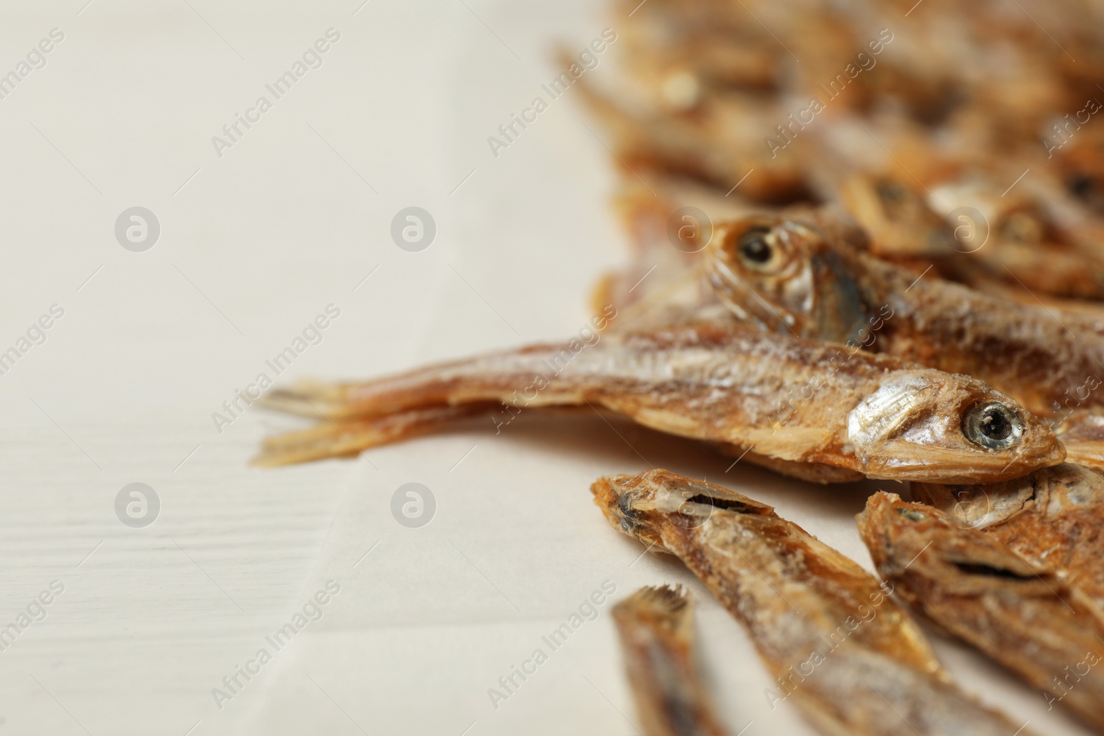 Photo of Dried anchovies on white wooden table, closeup. Space for text