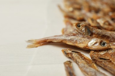 Photo of Dried anchovies on white wooden table, closeup. Space for text