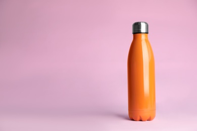 Stylish thermo bottle on pink background, space for text