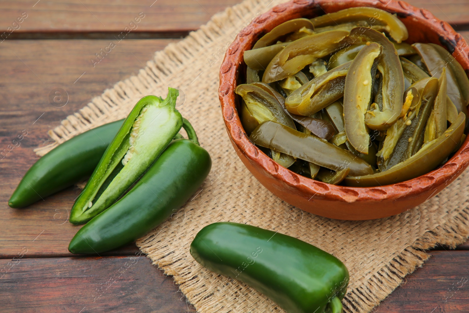 Photo of Fresh and pickled green jalapeno peppers on wooden table