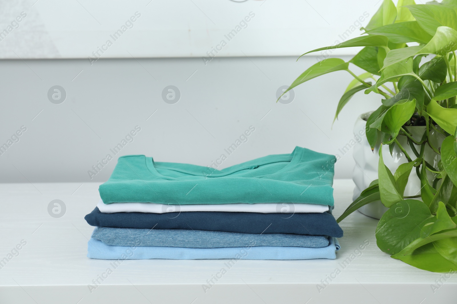 Photo of Sorting and organizing. Stack of different folded clothes on white table indoors