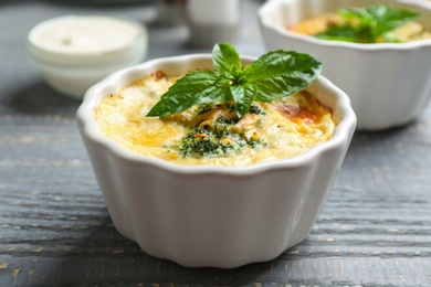 Photo of Tasty broccoli casserole in ramekin on wooden table, closeup