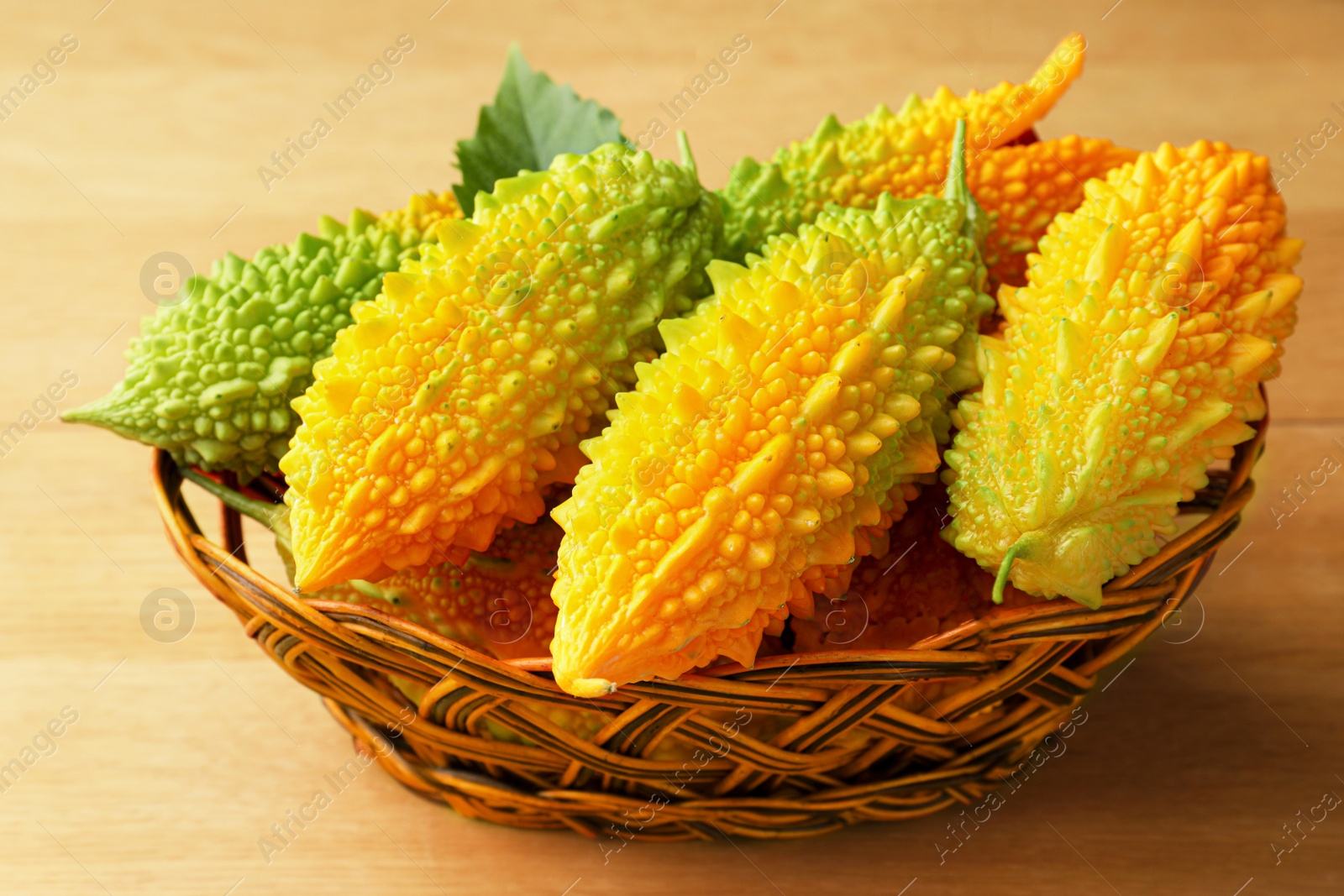 Photo of Basket with fresh bitter melons on wooden table, closeup